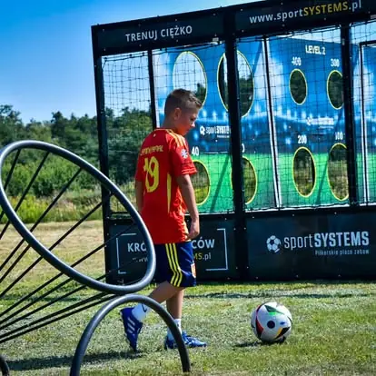 Młody piłkarz trenuje celność strzałów na urządzeniu Król Strzelców podczas pikniku sportowego.